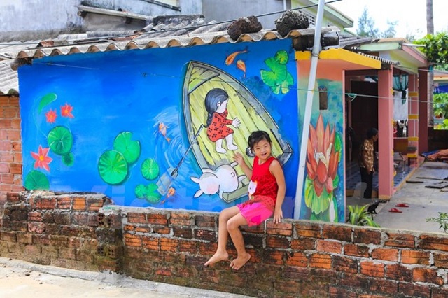 Cô bé vui cười khi bên ngôi nhà được khoác áo mới của mình- Làng bích họa Tam Thanh tại Việt Nam