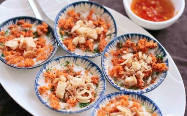 Những chiếc bánh màu trắng được rắc ruốc tôm hay ruốc bông cá ngừ, đậu phộng, lá hẹ thái nhỏ phía trên, vài mẩu bánh mì giòn tan (Ảnh ST)